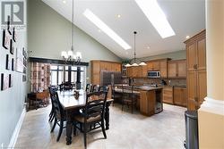 Dining space with light tile patterned floors, a skylight, high vaulted ceiling, and a notable chandelier - 