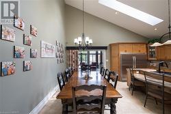 Dining area with a skylight, sink, high vaulted ceiling, a notable chandelier, and light tile patterned flooring - 