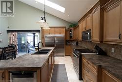 Kitchen featuring a skylight, sink, stainless steel appliances, pendant lighting, and decorative backsplash - 