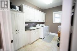 Clothes washing area featuring washer and dryer, cabinets, and sink - 