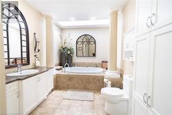 Bathroom featuring toilet, vanity, tiled bath, and ornate columns - 