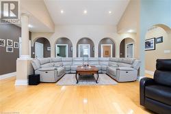 Living room featuring light wood-type flooring, high vaulted ceiling, and decorative columns - 