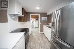 Kitchen with white cabinetry, stainless steel appliances, tasteful backsplash, light hardwood / wood-style floors, and dark brown cabinets - 