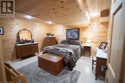 Bedroom with wood walls, light hardwood / wood-style floors, and wooden ceiling - 