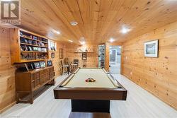 Playroom featuring billiards, wooden walls, built in features, light hardwood / wood-style floors, and wood ceiling - 