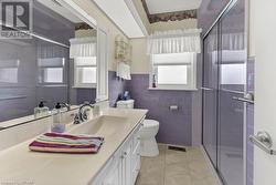 Bathroom featuring an enclosed shower, vanity, toilet, and tile walls - 