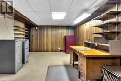 Carpeted office with a drop ceiling and wooden walls - 