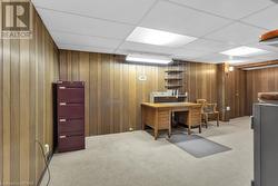 Carpeted office with a drop ceiling and wooden walls - 