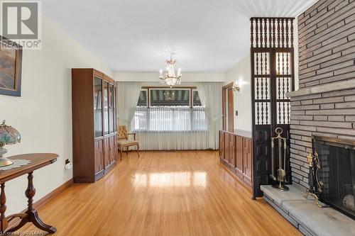 Unfurnished living room featuring hardwood / wood-style floors, a chandelier, and a brick fireplace - 133 Fairview Crescent, Woodstock, ON - Indoor With Fireplace