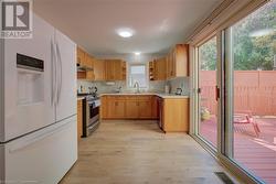 Kitchen featuring sink, stainless steel gas stove, white refrigerator with ice dispenser, and light wood-type flooring - 