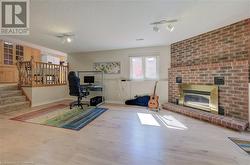 Office with a textured ceiling, rail lighting, light hardwood / wood-style floors, and a brick fireplace - 