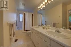 Full bathroom with tile patterned flooring, shower / bath combination with curtain, vanity, and toilet - 