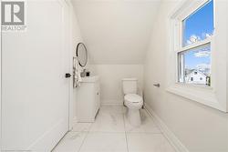 Bathroom featuring toilet, vanity, vaulted ceiling, and plenty of natural light - 