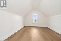 Bonus room with a textured ceiling, light hardwood / wood-style flooring, and lofted ceiling - 