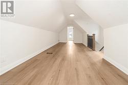 Bonus room featuring a textured ceiling, light wood-type flooring, and lofted ceiling - 