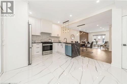 Kitchen featuring decorative light fixtures, stainless steel appliances, white cabinetry, and light hardwood / wood-style flooring - 45 Munroe Street, Hamilton, ON - Indoor Photo Showing Kitchen With Upgraded Kitchen