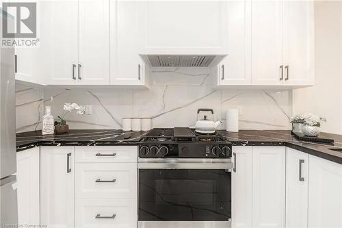 Kitchen featuring white cabinets, premium range hood, backsplash, and appliances with stainless steel finishes - 45 Munroe Street, Hamilton, ON - Indoor Photo Showing Kitchen With Upgraded Kitchen