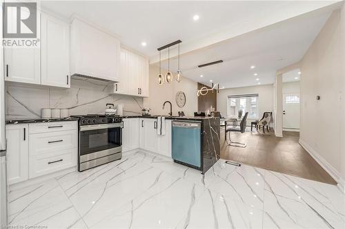 Kitchen featuring kitchen peninsula, stainless steel appliances, decorative light fixtures, white cabinets, and light hardwood / wood-style floors - 45 Munroe Street, Hamilton, ON - Indoor Photo Showing Kitchen With Upgraded Kitchen