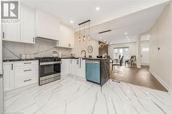 Kitchen featuring kitchen peninsula, stainless steel appliances, decorative light fixtures, white cabinets, and light hardwood / wood-style floors - 