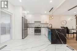 Kitchen with white cabinets, appliances with stainless steel finishes, pendant lighting, and custom exhaust hood - 