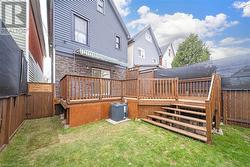 Rear view of house featuring a yard, central AC, and a wooden deck - 