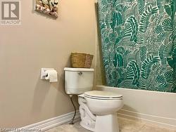 Bathroom featuring tile patterned flooring, shower / tub combo, and toilet - 