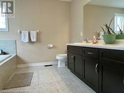 Bathroom featuring tile patterned floors, vanity, toilet, and tiled bath - 