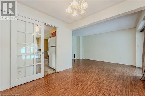 Empty room featuring a notable chandelier and light wood-type flooring - 10 Fenwick Court, Kitchener, ON 