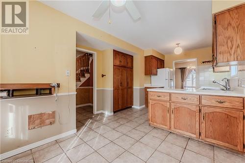 Kitchen with backsplash, ceiling fan, sink, light tile patterned floors, and white fridge - 10 Fenwick Court, Kitchener, ON 