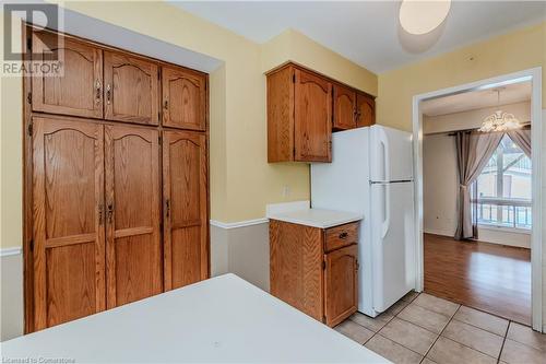 Kitchen featuring light hardwood / wood-style flooring, white fridge, decorative light fixtures, and a notable chandelier - 10 Fenwick Court, Kitchener, ON 