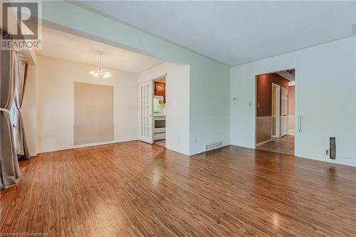 Unfurnished living room featuring hardwood / wood-style flooring and an inviting chandelier - 10 Fenwick Court, Kitchener, ON 