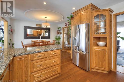 Kitchen with light stone countertops, stainless steel fridge with ice dispenser, dark hardwood / wood-style floors, and decorative light fixtures - 19 Halifax Drive, Kitchener, ON - Indoor Photo Showing Kitchen