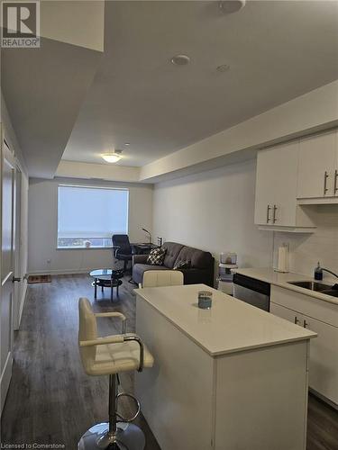 Kitchen with white cabinetry, a kitchen island, stainless steel dishwasher, and dark hardwood / wood-style floors - 251 Northfield Drive E Unit# 401, Waterloo, ON - Indoor Photo Showing Kitchen