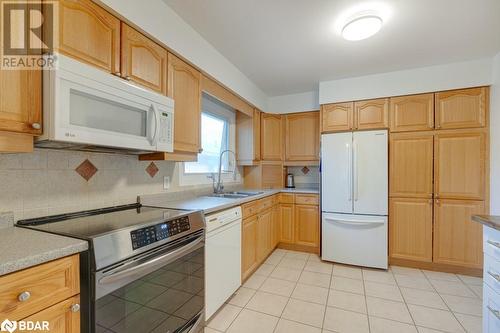 Kitchen with decorative backsplash, sink, light tile patterned floors, and white appliances - 47 Westfield Drive, St. Catharines, ON - Indoor Photo Showing Kitchen With Double Sink