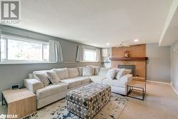 Carpeted living room featuring a textured ceiling, a brick fireplace, and ceiling fan - 