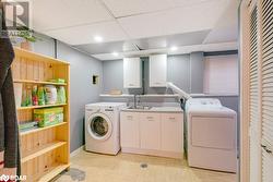 Laundry room featuring cabinets, independent washer and dryer, sink, and light parquet flooring - 