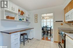 Kitchen featuring a chandelier, white appliances, white cabinetry, and hanging light fixtures - 