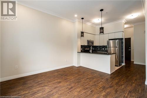 Kitchen with dark hardwood / wood-style floors, kitchen peninsula, stainless steel appliances, and hanging light fixtures - 112 King Street E Unit# 305, Hamilton, ON - Indoor Photo Showing Kitchen