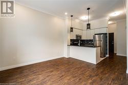 Kitchen with dark hardwood / wood-style floors, kitchen peninsula, stainless steel appliances, and hanging light fixtures - 