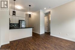 Kitchen with backsplash, dark wood-type flooring, hanging light fixtures, appliances with stainless steel finishes, and white cabinetry - 