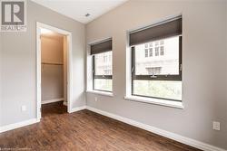 Unfurnished bedroom with a spacious closet, a closet, and dark wood-type flooring - 