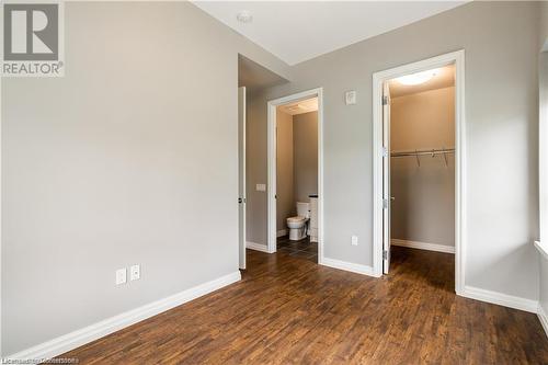 Unfurnished bedroom featuring connected bathroom, a walk in closet, a closet, and dark hardwood / wood-style flooring - 112 King Street E Unit# 305, Hamilton, ON - Indoor Photo Showing Other Room