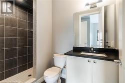 Bathroom featuring a tile shower, vanity, and toilet - 