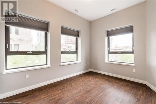 Empty room featuring dark wood-type flooring - 112 King Street E Unit# 305, Hamilton, ON - Indoor Photo Showing Other Room