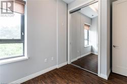 Unfurnished bedroom with a closet, dark wood-type flooring, and multiple windows - 