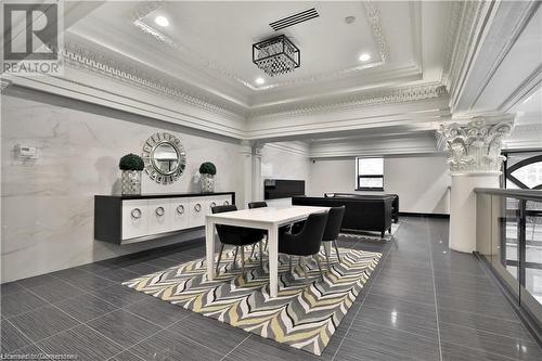 Dining space featuring a raised ceiling, crown molding, dark tile patterned floors, tile walls, and decorative columns - 112 King Street E Unit# 305, Hamilton, ON - Indoor Photo Showing Other Room