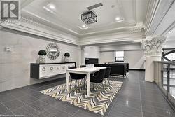 Dining space featuring a raised ceiling, crown molding, dark tile patterned floors, tile walls, and decorative columns - 