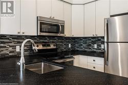 Kitchen with tasteful backsplash, sink, white cabinets, and appliances with stainless steel finishes - 