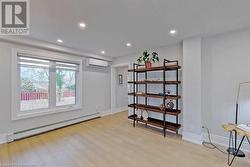 Basement featuring light hardwood / wood-style floors, a wall unit AC, and baseboard heating - 