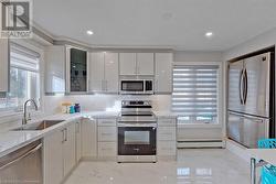 Kitchen featuring tasteful backsplash, sink, appliances with stainless steel finishes, and a baseboard radiator - 